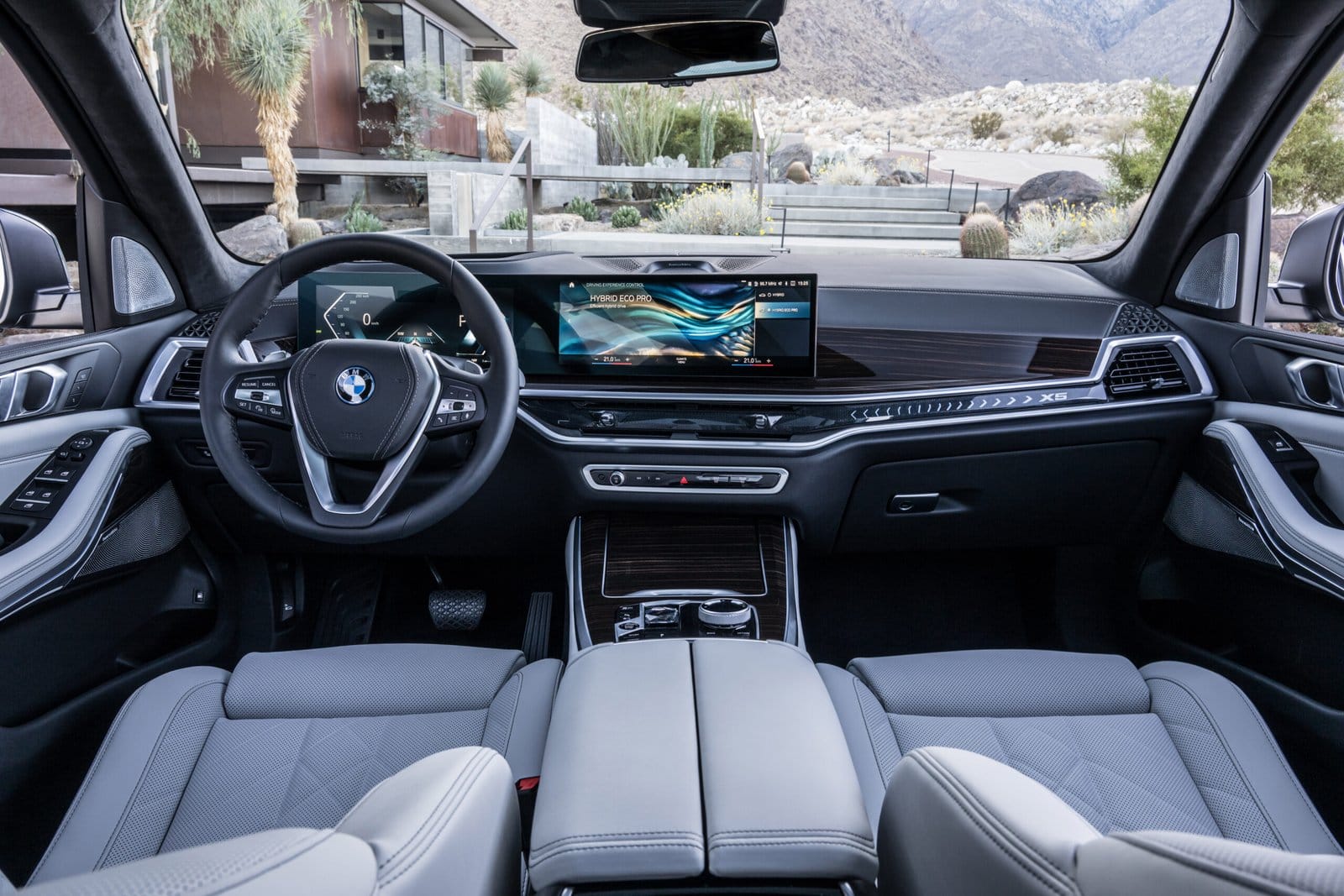 Interior view of the BMW X5 Plug-in Hybrid electric vehicle showing the steering wheel, digital display, and center console with a mountain view outside.