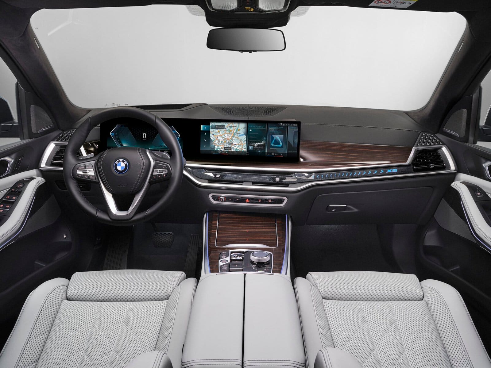 The dashboard and infotainment screen of the BMW X5 Plug-in Hybrid electric vehicle, featuring digital navigation and climate controls.