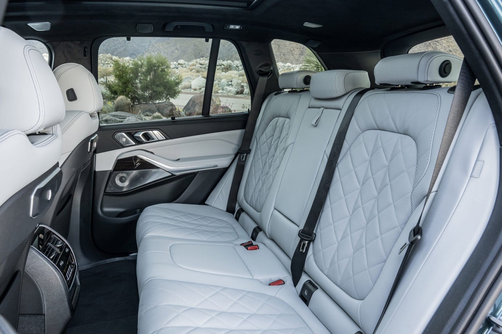 Quilted leather rear seats of the BMW X5 Plug-in Hybrid electric vehicle, viewed from the passenger side with a desert background outside the window.