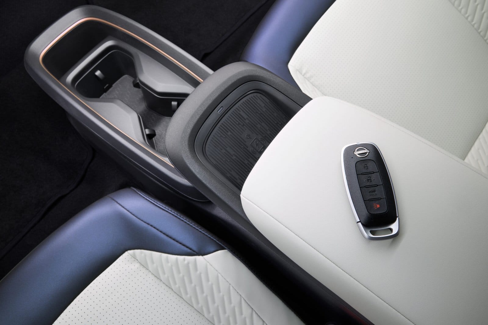 Close-up of the Nissan Leaf electric vehicle’s center console with wireless charger, cupholders, and key fob on armrest