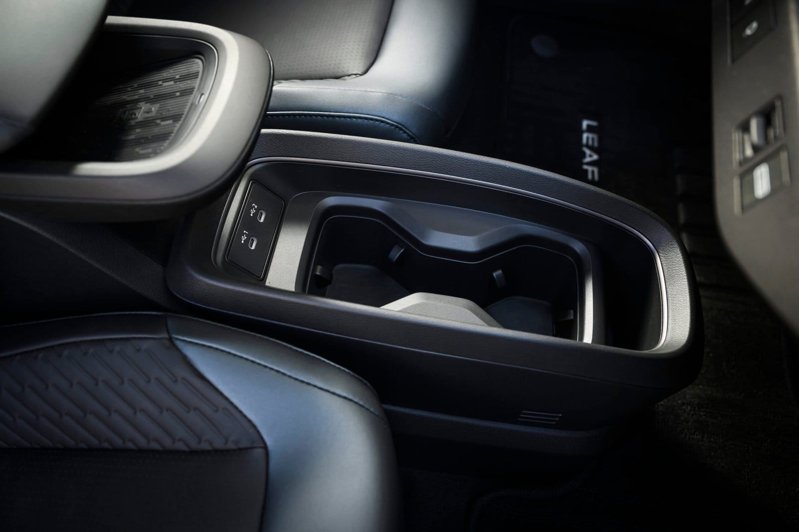Close-up of the Nissan Leaf electric vehicle’s center console showing dual cupholders and USB ports