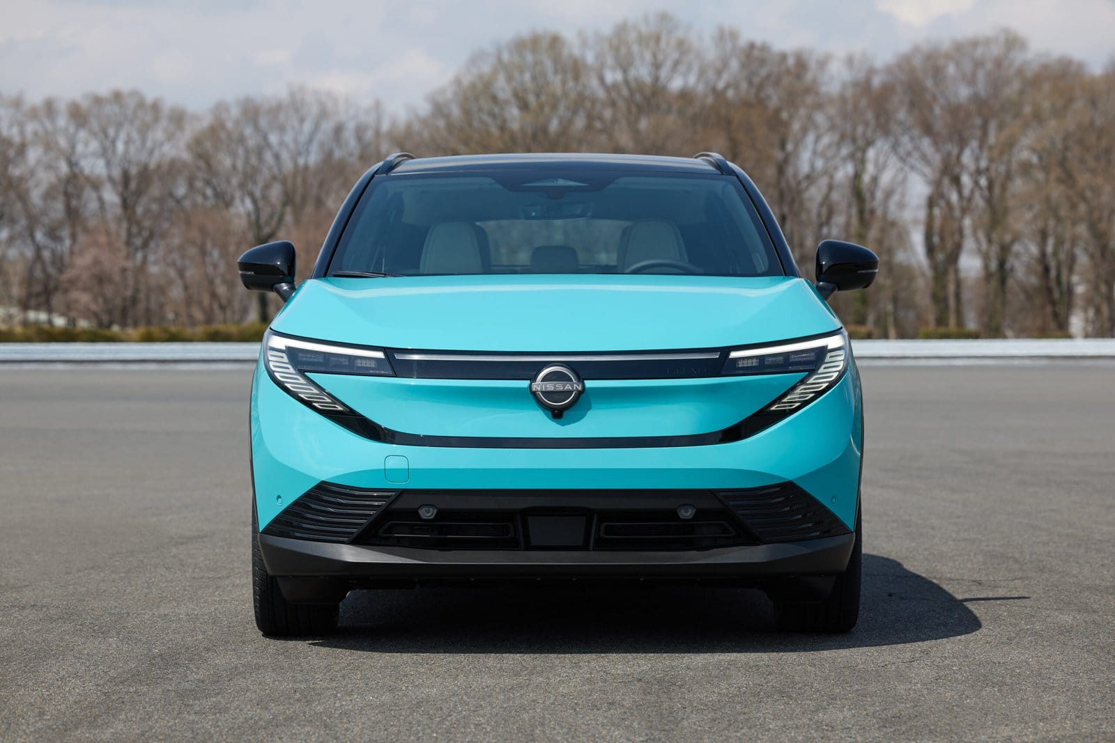 Nissan Leaf electric vehicle photographed head-on while parked on an empty asphalt surface
