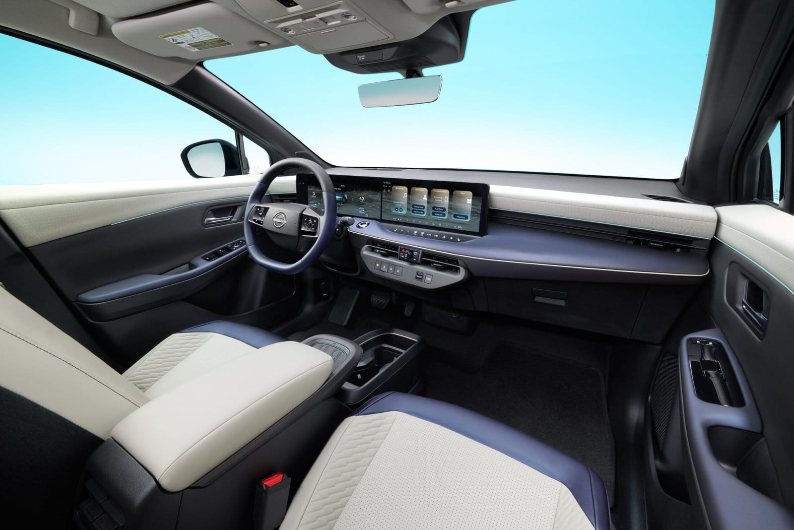 Interior of the Nissan Leaf electric vehicle showing dashboard, steering wheel, and front seats in a two-tone finish