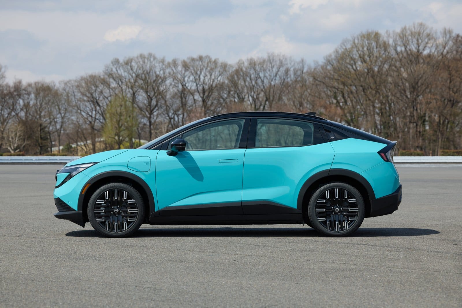 Nissan Leaf electric vehicle in blue parked on an asphalt lot with a clear left-side view