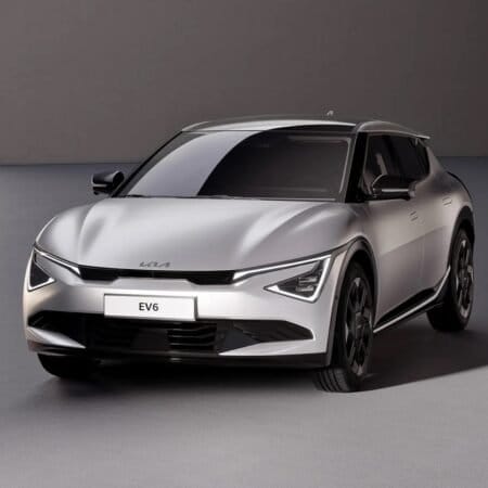 A silver Kia EV6 electric vehicle with its updated 2024 facelift, parked in a modern, minimalist indoor space with soft lighting.