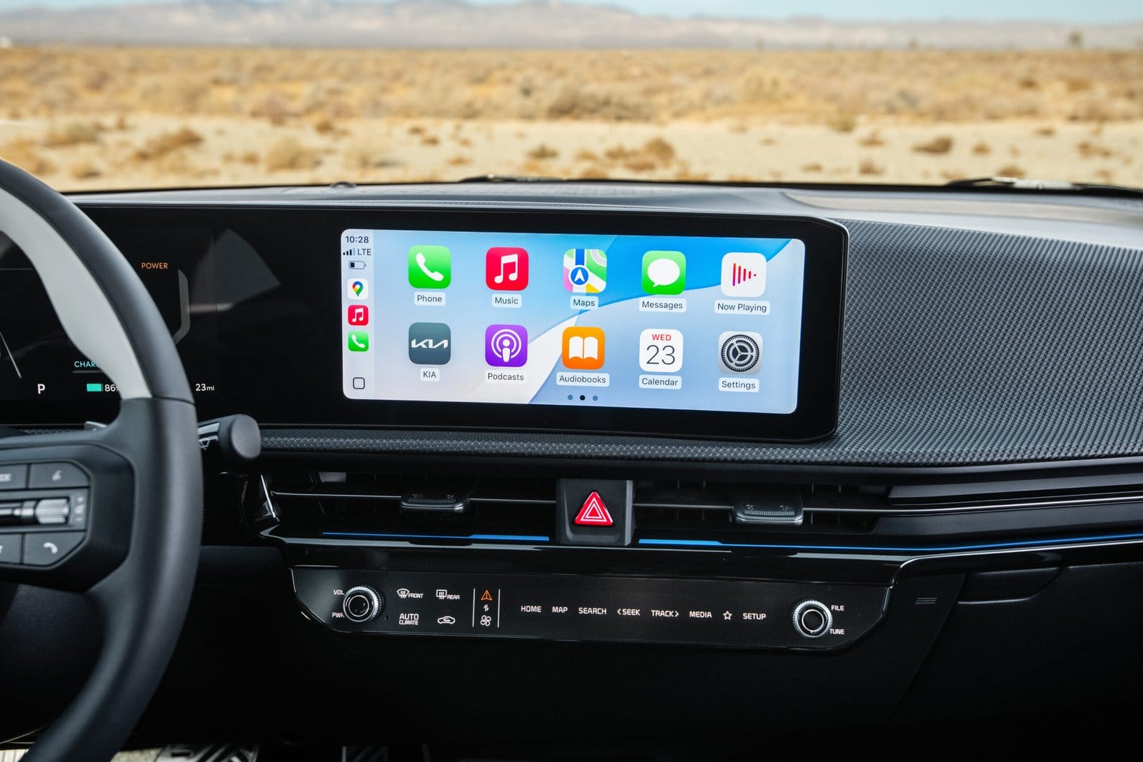 The infotainment screen of the Kia EV6 electric vehicle displaying app icons, with a desert landscape visible through the windshield.