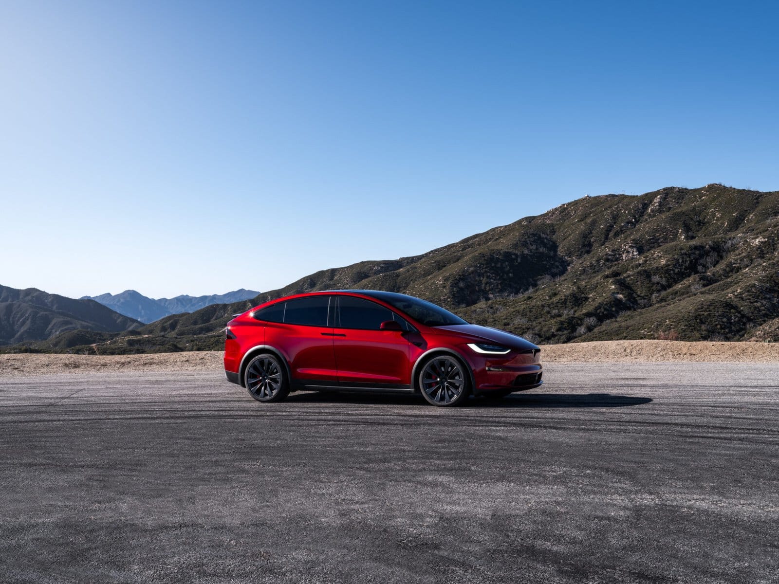red tesla model x electric vehicle mountain background