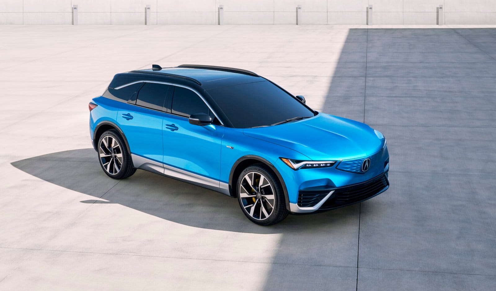 A blue Acura ZDX electric vehicle parked in a spacious open area, showcasing its sleek design and modern styling.