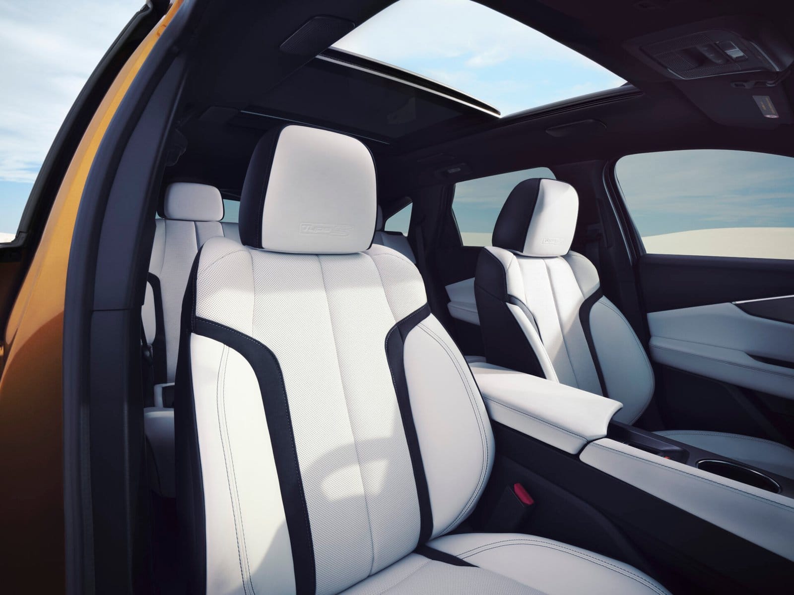 Close-up view of the Acura ZDX electric vehicle's front seats, featuring white leather upholstery with black accents and a panoramic sunroof in the background.