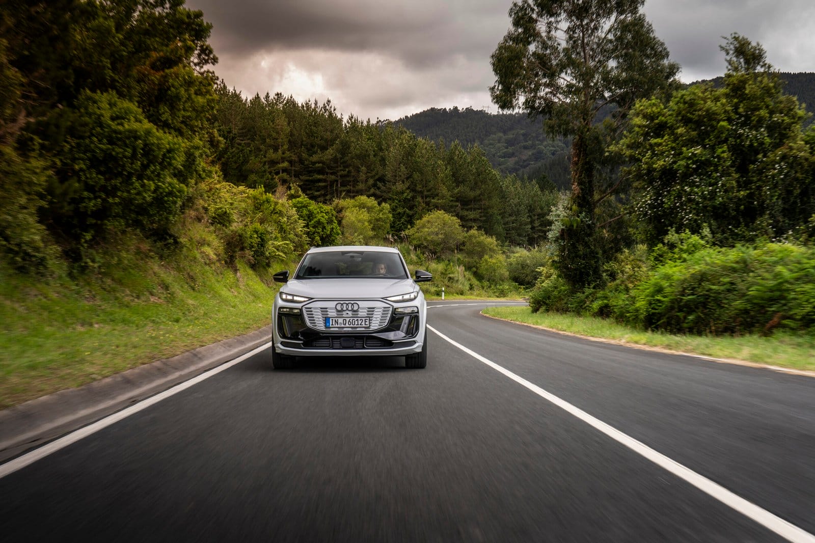 Front view of Audi Q6 electric vehicle driving through forest road