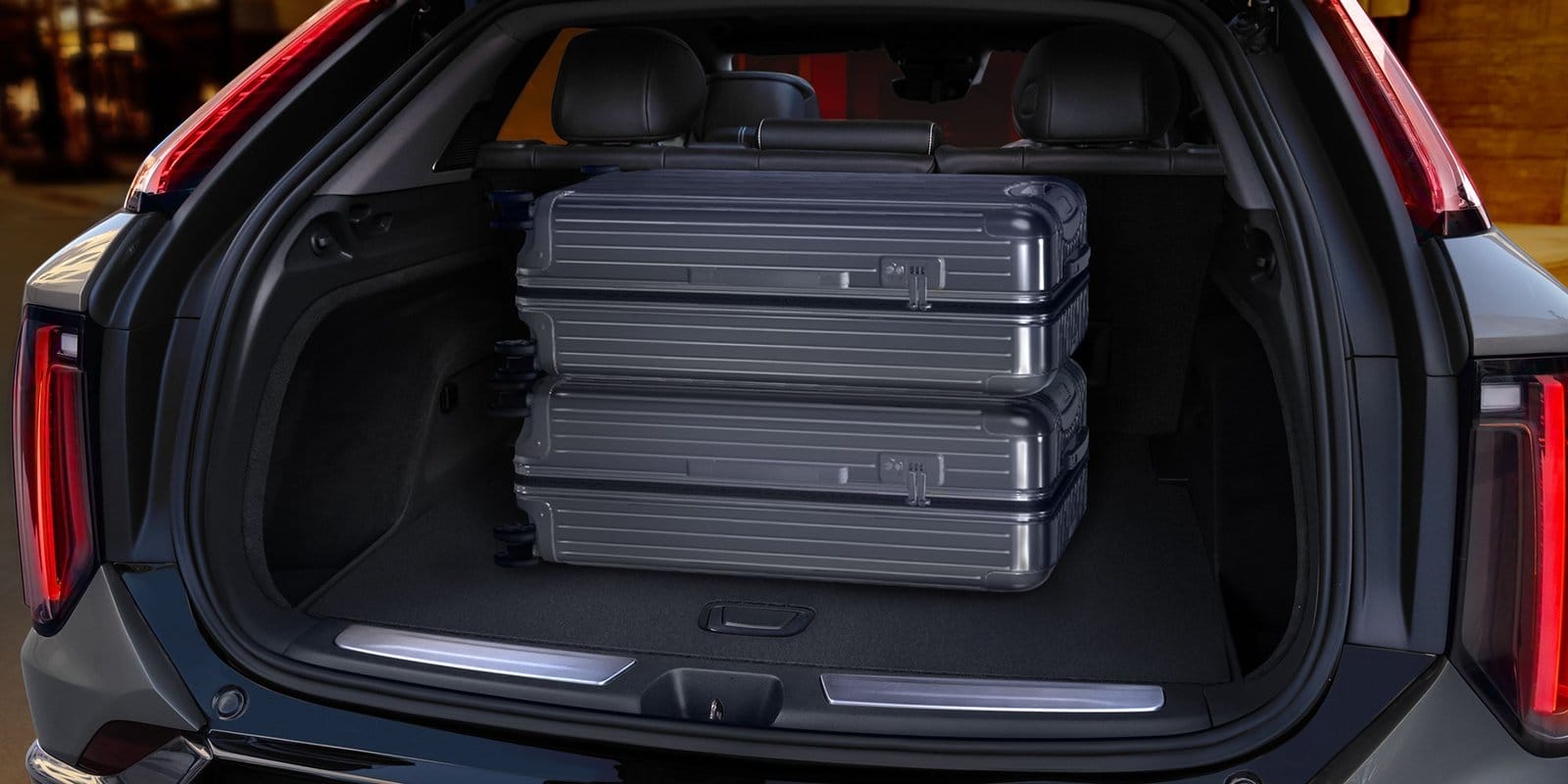 Open trunk of Cadillac Optiq electric vehicle showing two stacked hard-shell suitcases
