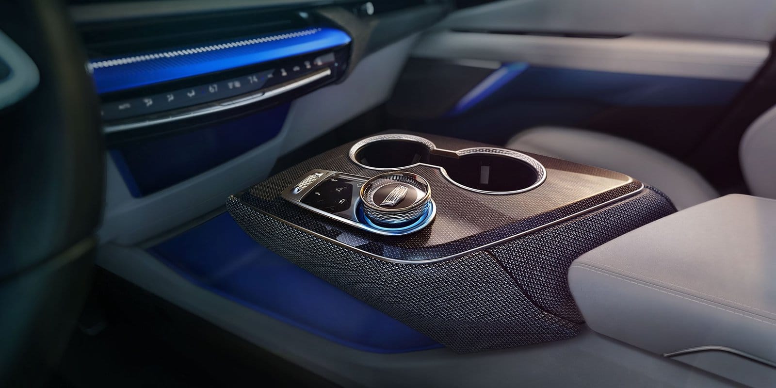 Interior view of Cadillac Optiq electric vehicle center console with rotary dial and cup holders