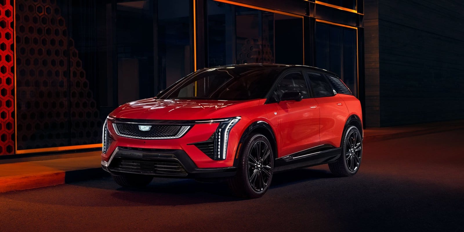 Front three-quarter view of the Cadillac Optiq electric vehicle parked on a city street at night