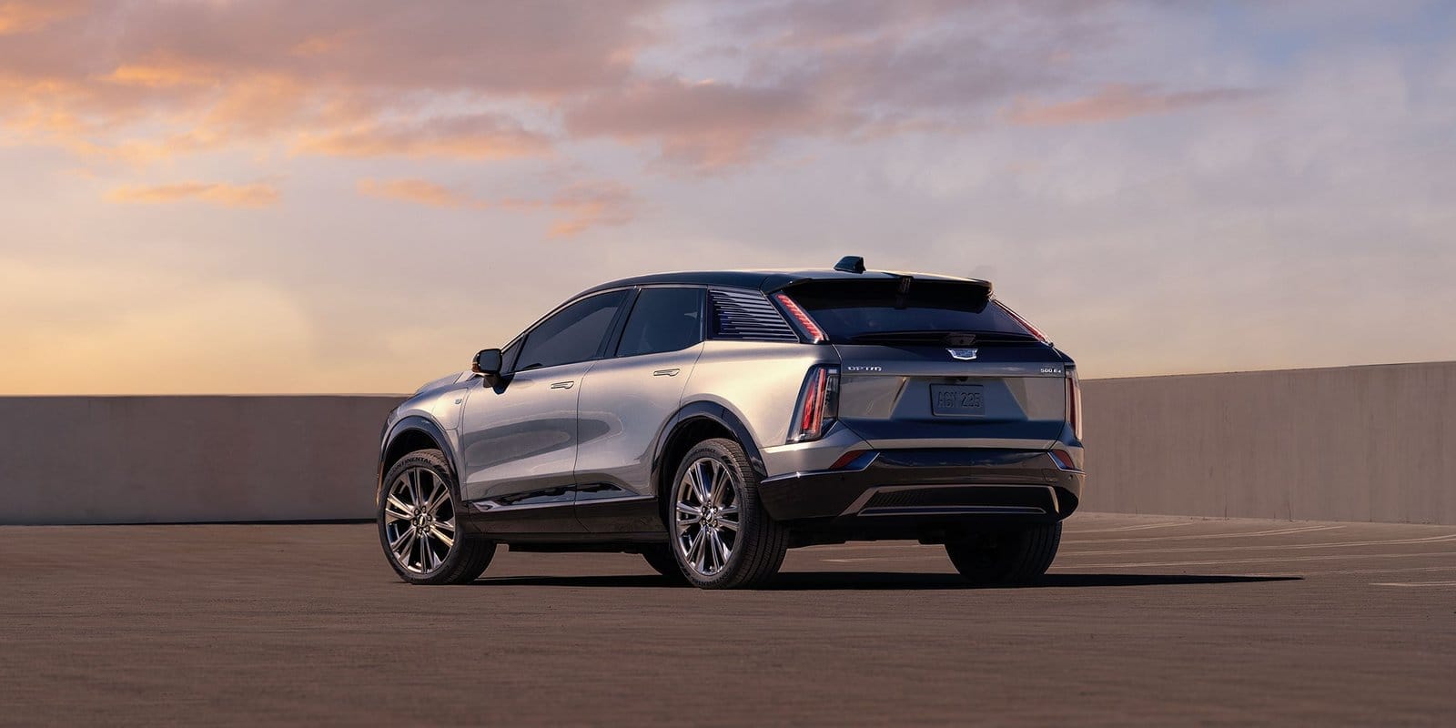 Rear three-quarter view of the Cadillac Optiq electric vehicle from the driver's side at sunset in an open lot
