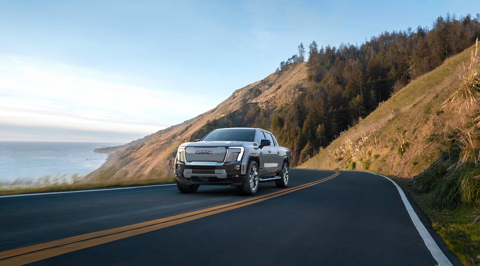 GMC Sierra EV electric vehicle cruising on a scenic coastal highway
