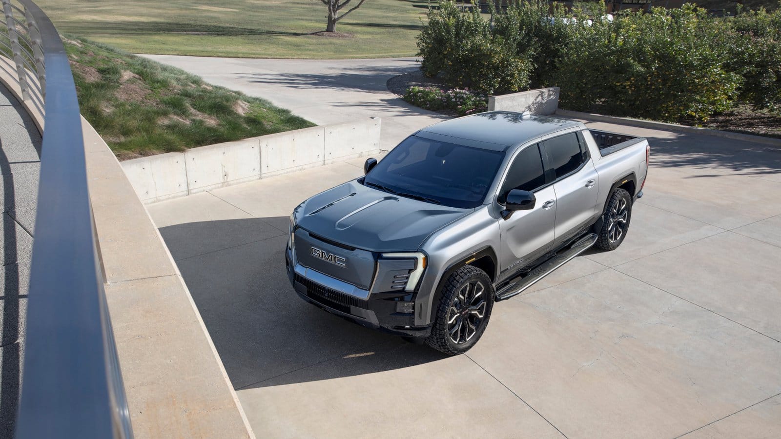 Overhead view of GMC Sierra EV Denali electric vehicle parked on a concrete driveway with trees and landscaping in the background