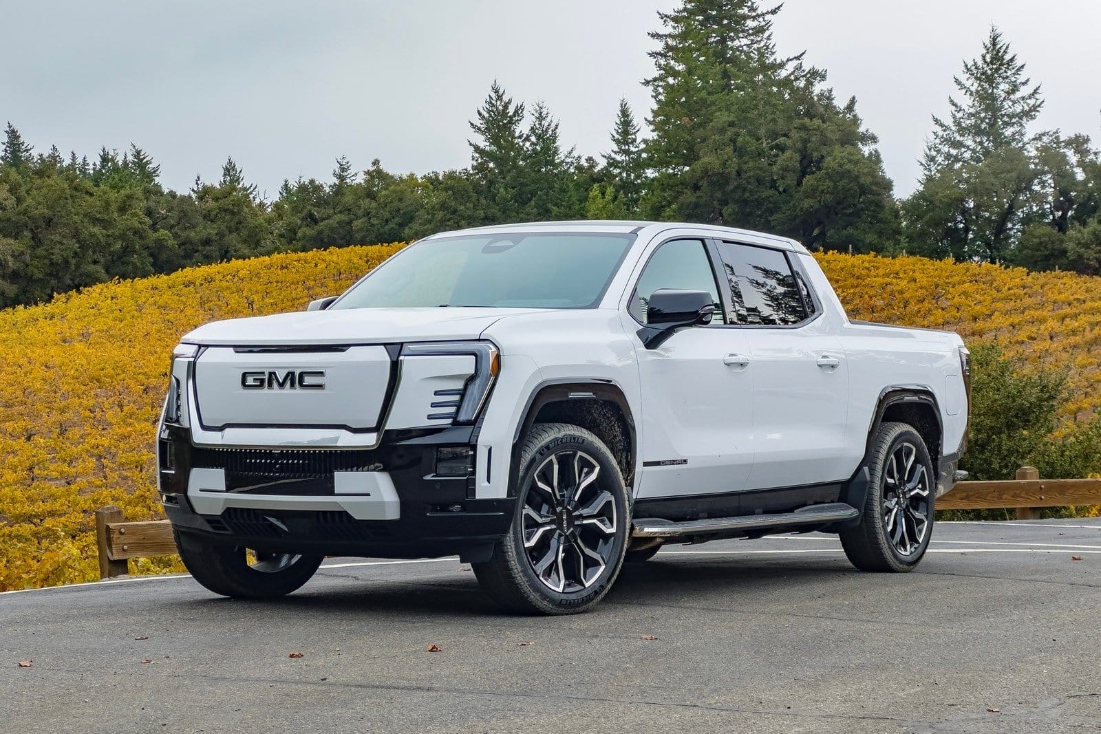 Front angle view of GMC Sierra EV electric vehicle parked near vineyard with yellow leaves