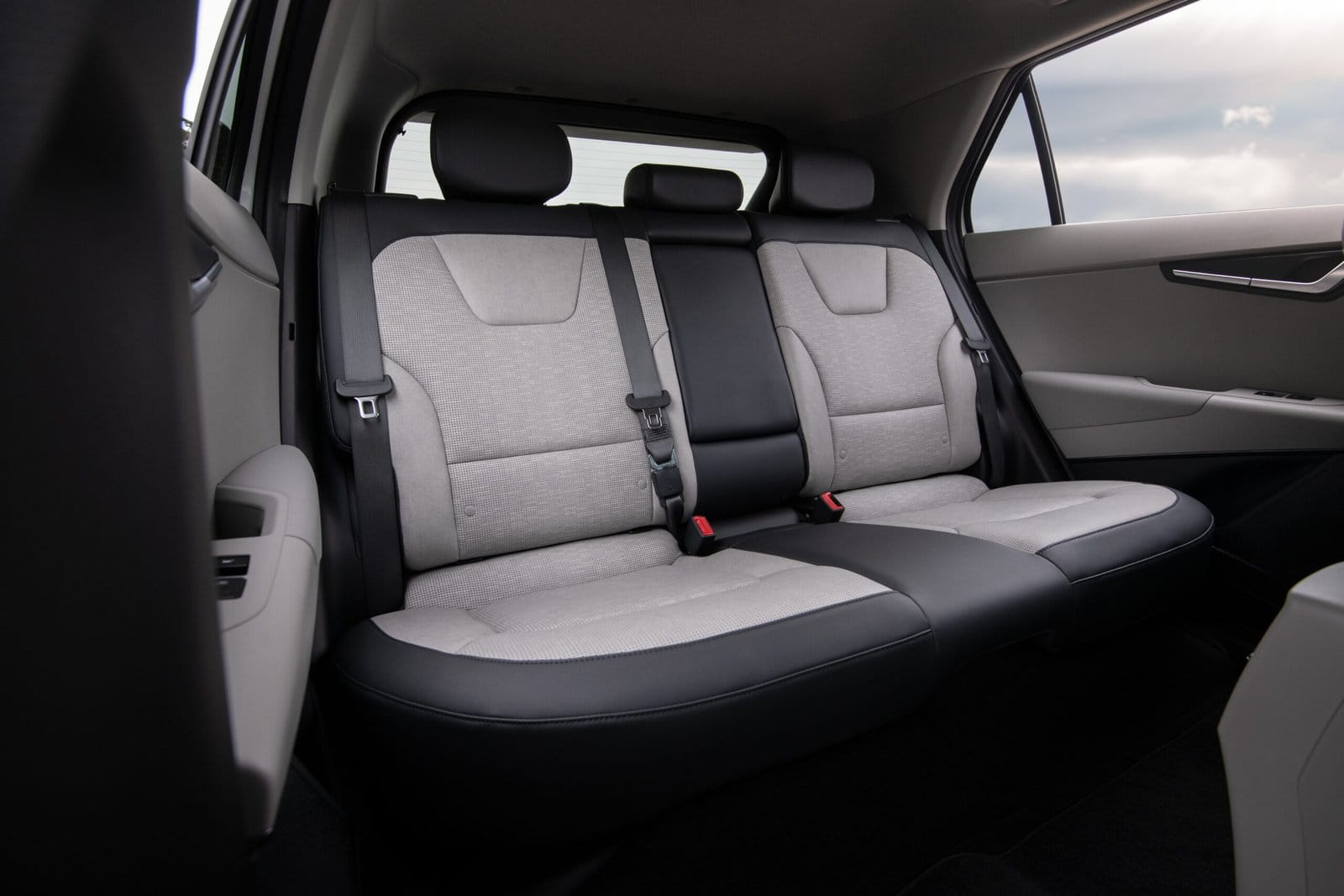 Rear seats of the Kia Niro EV electric vehicle showing fabric upholstery, seatbelts, and flat floor design
