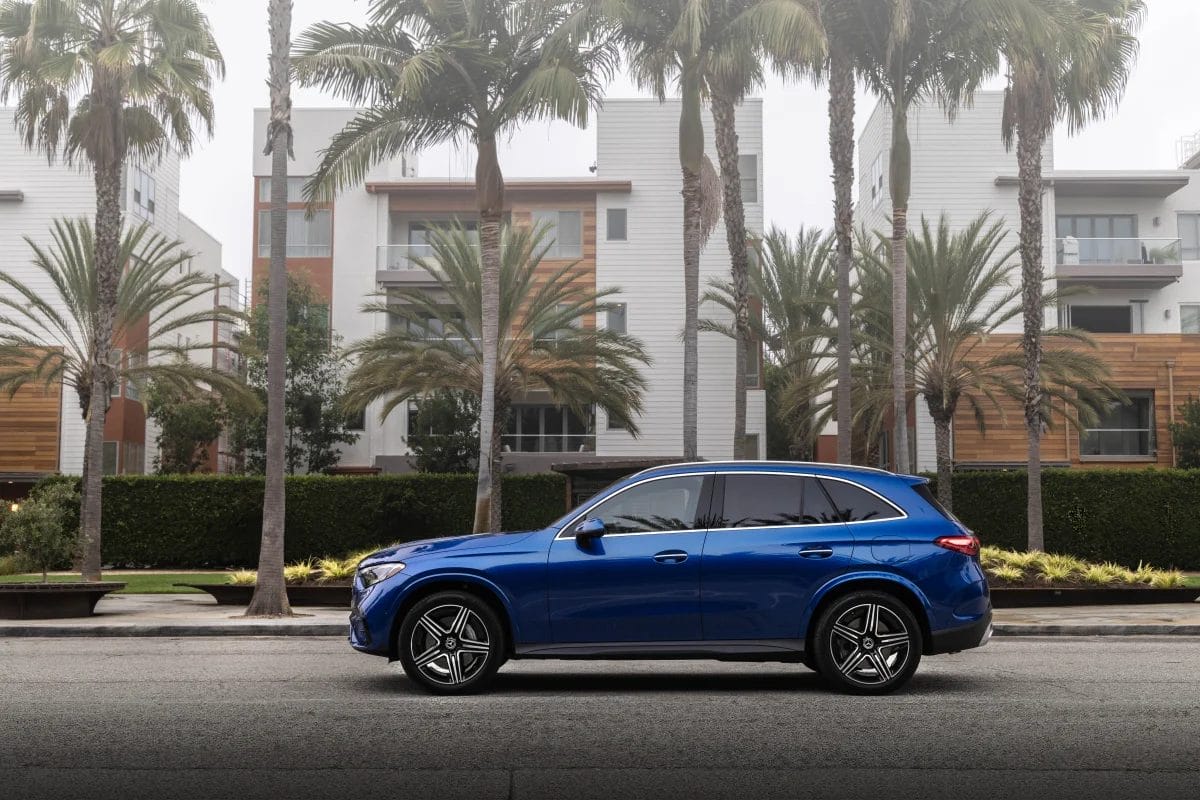 Blue Mercedes-Benz GLC PHEV electric vehicle parked in front of modern residential buildings and palm trees
