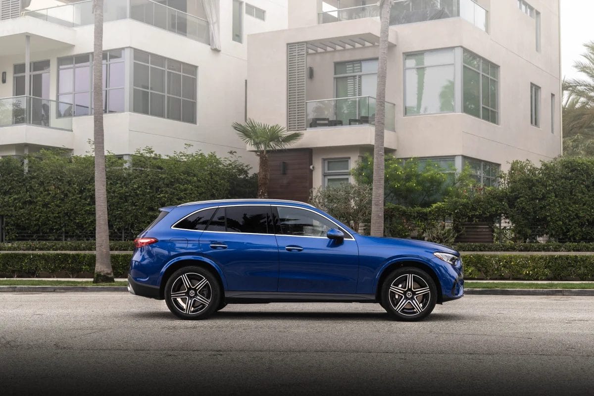 Blue Mercedes-Benz GLC PHEV electric vehicle parked beside a residential building in a modern city neighborhood