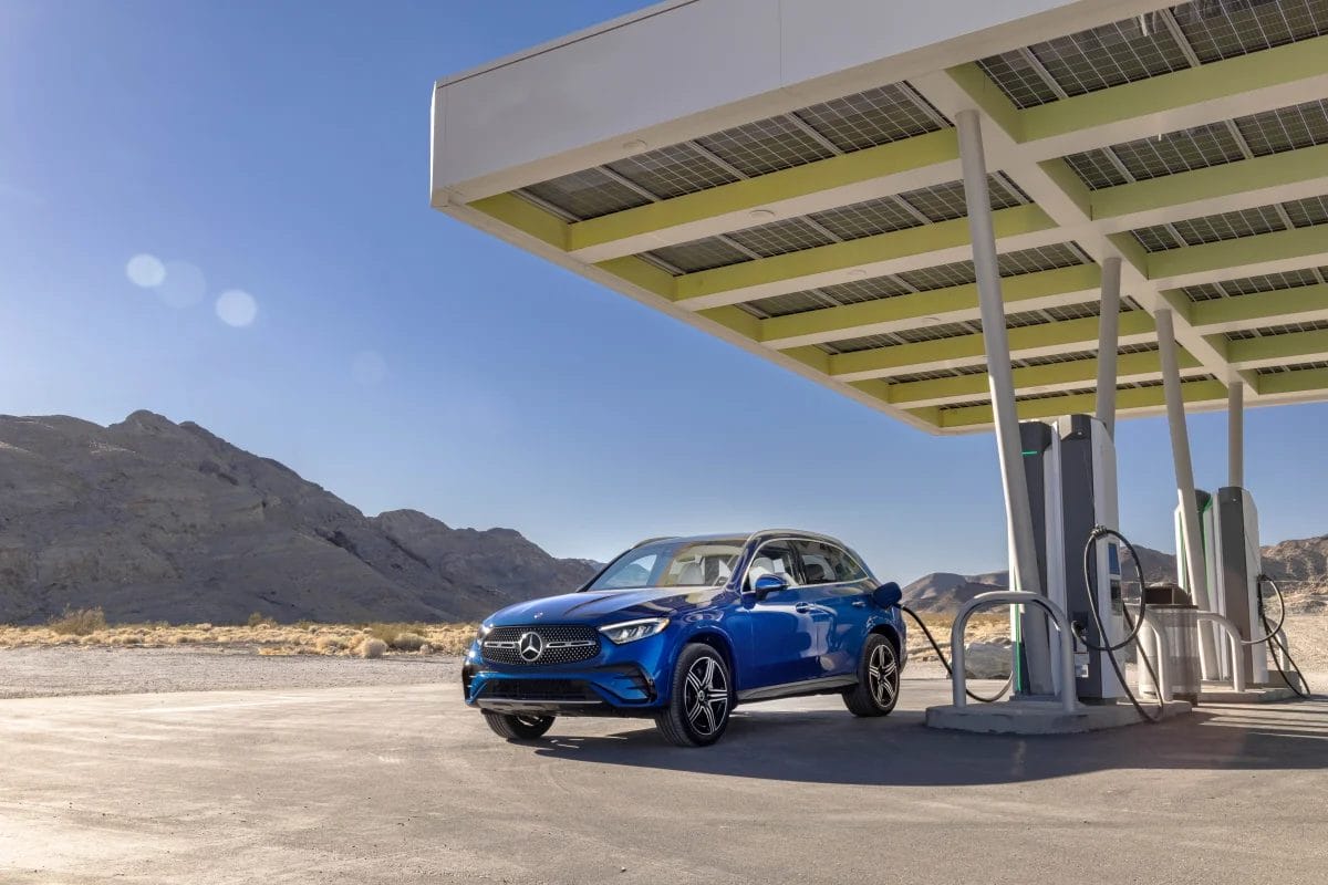 2025 Mercedes-Benz GLC 350e electric vehicle plugged in at a charging station beneath solar panels in a desert landscape