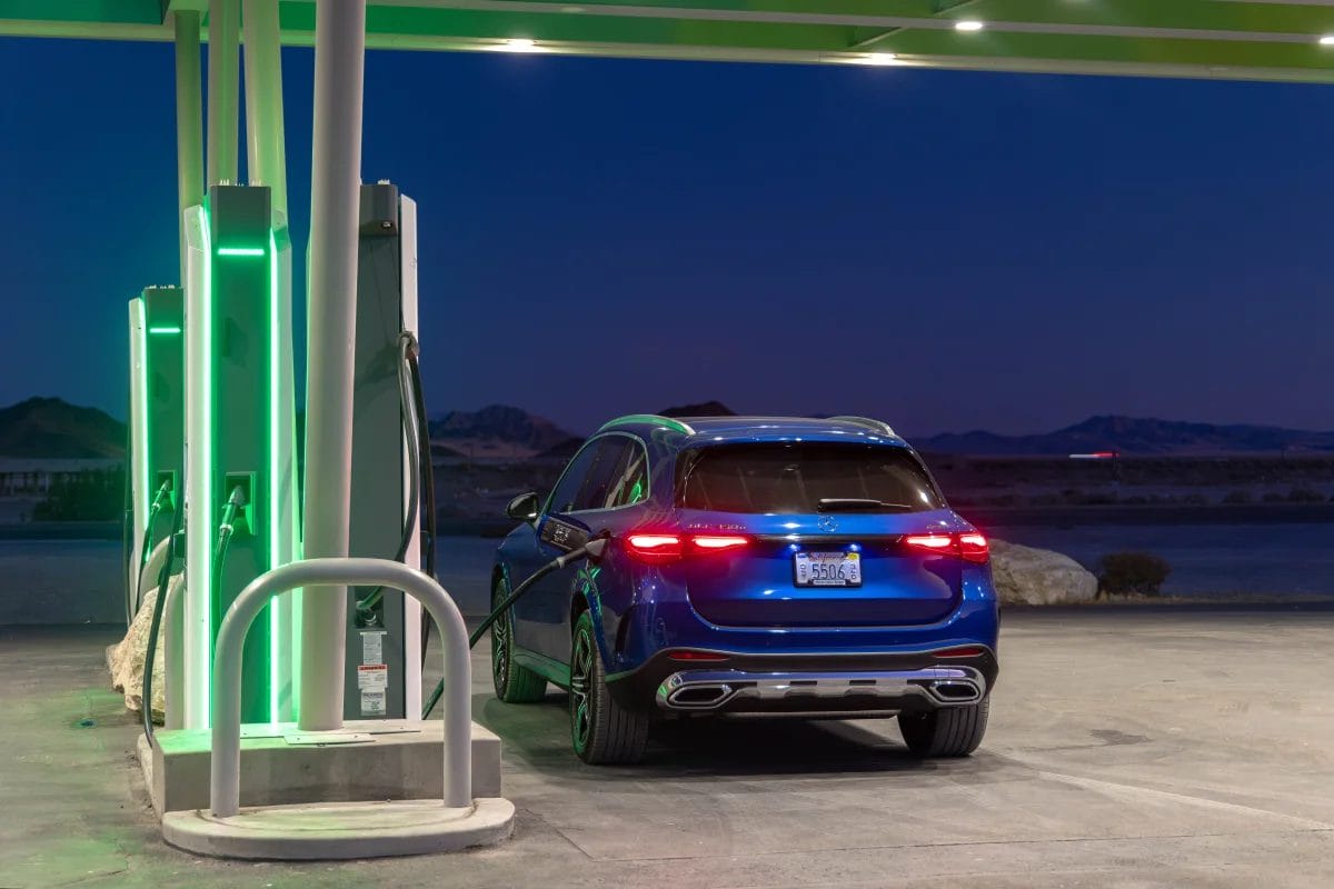 Rear view of 2025 Mercedes-Benz GLC 350e electric vehicle charging at an illuminated station during night-time in a desert area