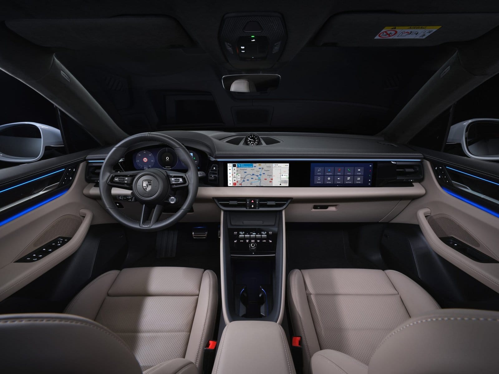 Driver’s view of the Porsche Macan EV electric vehicle showing digital instrument cluster, full-width infotainment screen, and illuminated interior accents