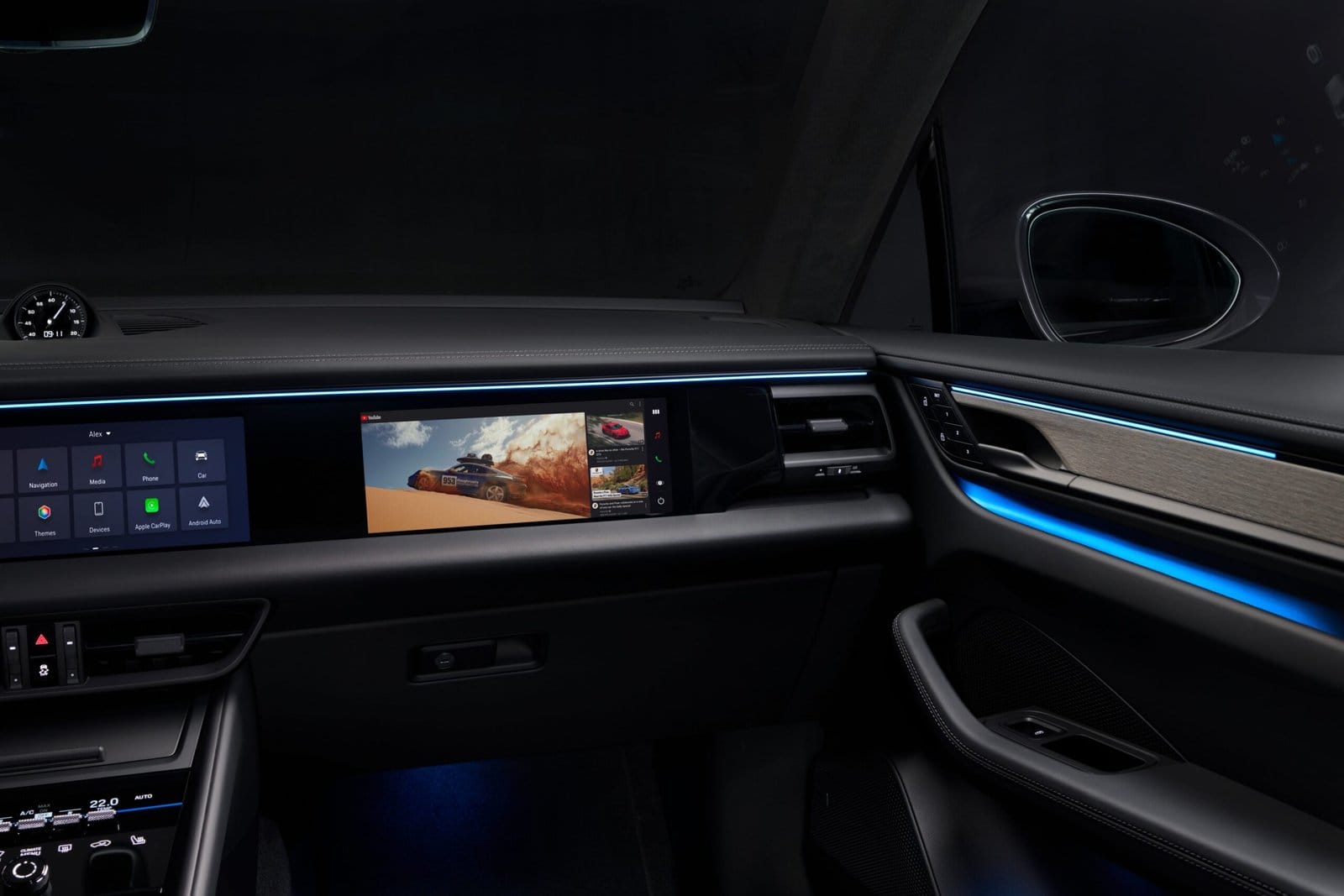 Interior view of Porsche Macan EV electric vehicle showing dual front displays, ambient lighting, and passenger screen interface