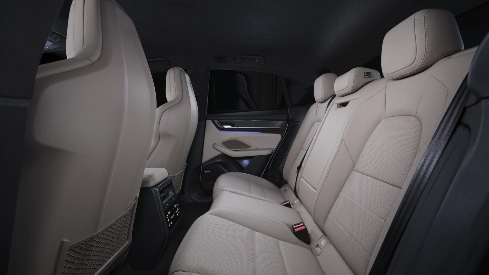 Rear passenger compartment of the Porsche Macan EV electric vehicle featuring beige leather seats and ambient lighting on door panels