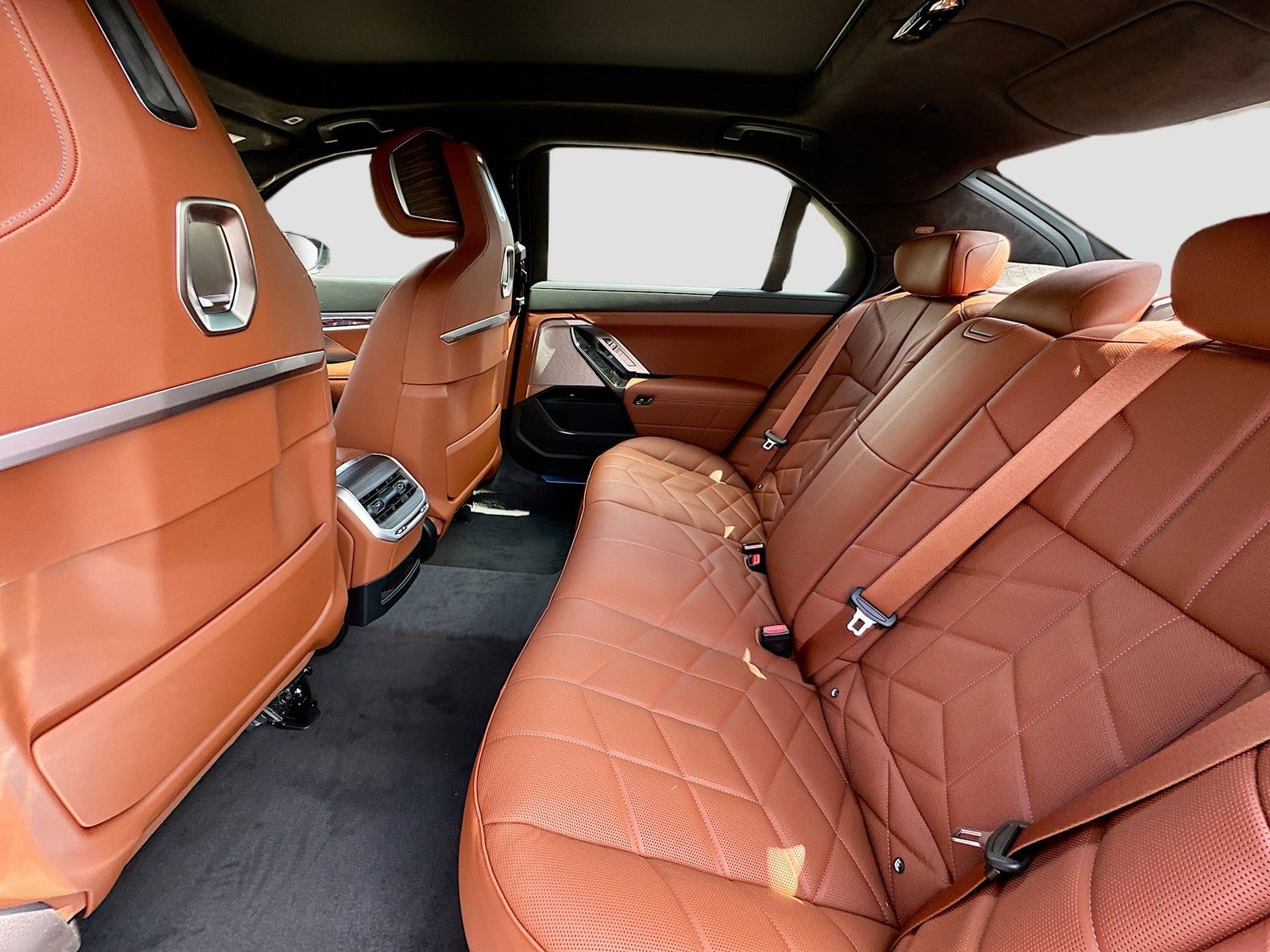 Rear passenger seat area of the BMW 750e plug-in hybrid vehicle with quilted brown leather upholstery and spacious legroom