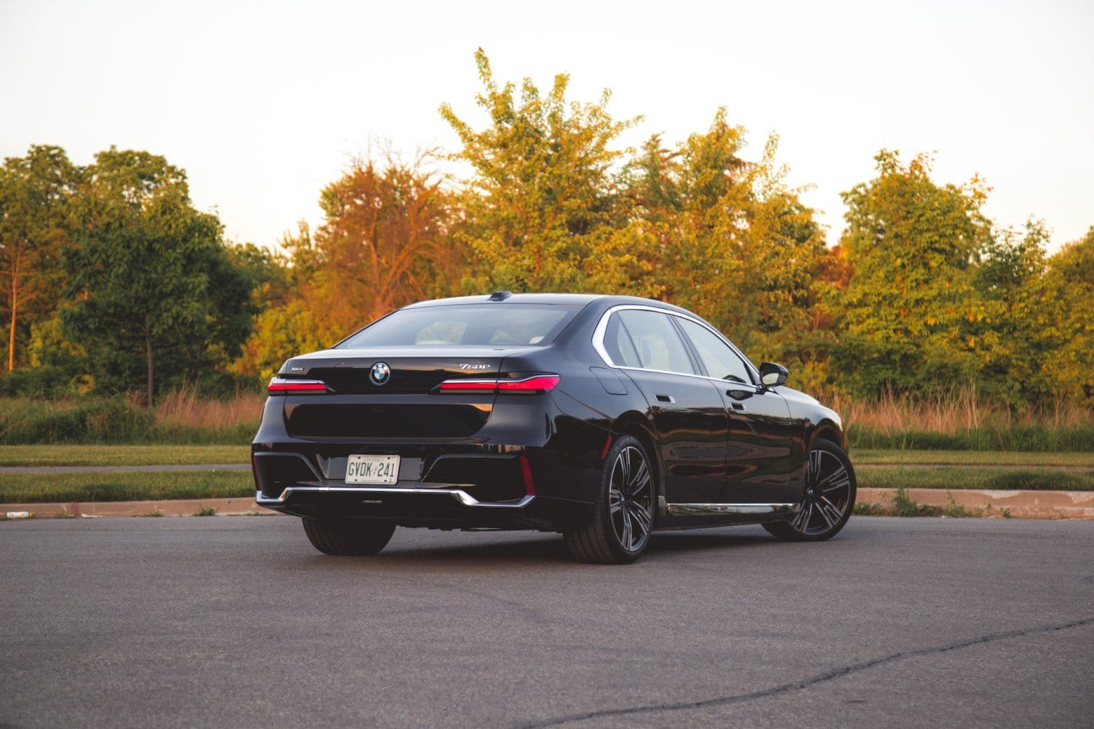 Rear and side profile of the BMW 750e xDrive Plug-in Hybrid parked near a grassy area
