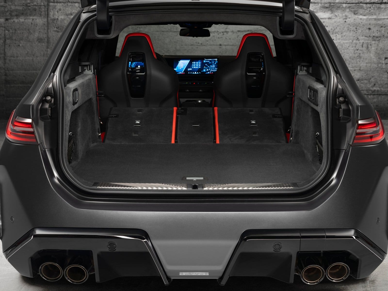BMW M5 Touring Plug-in Hybrid rear view showing cargo space with folded rear seats and digital dashboard