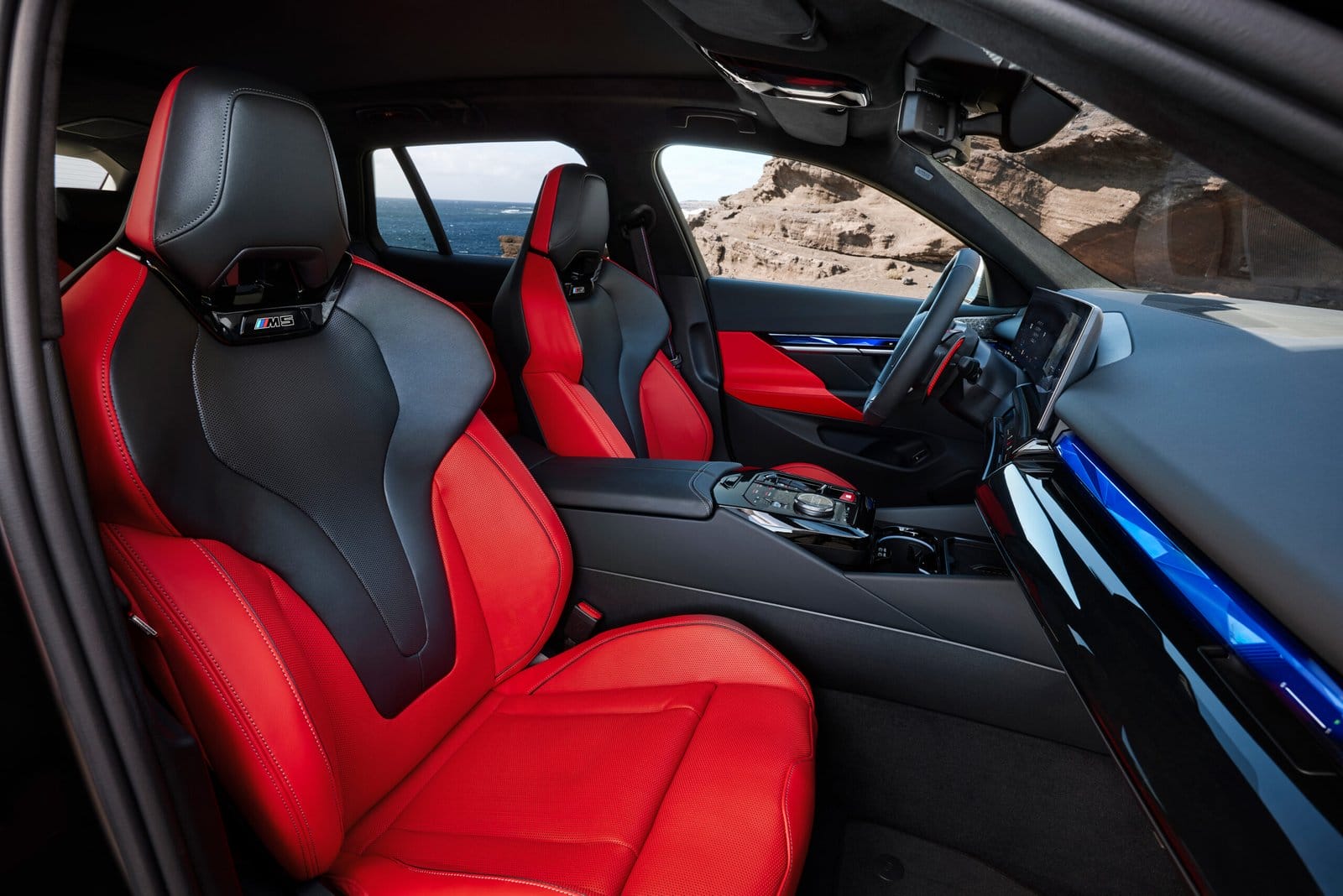 Close-up of BMW M5 Touring Plug-in Hybrid red and black leather front sport seats with center console and ambient lighting
