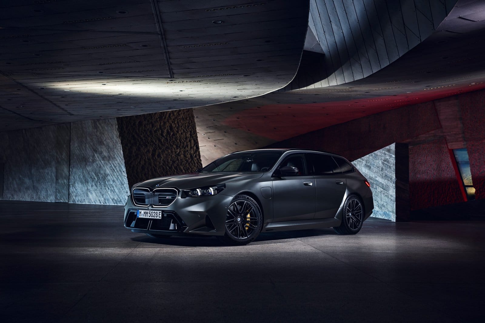 BMW M5 Touring Plug-in Hybrid parked under sculptural architecture at night in dramatic lighting