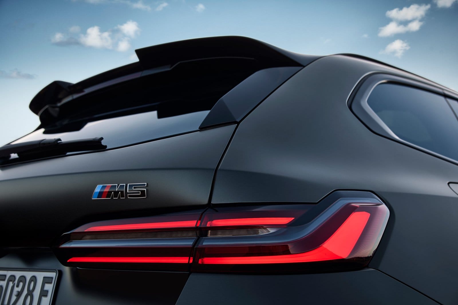 Close-up of BMW M5 Touring Plug-in Hybrid rear M5 badge and illuminated LED taillight