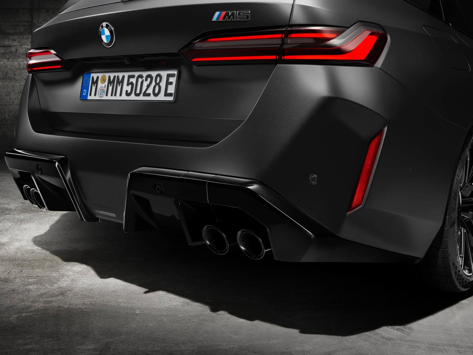 Close-up of the rear section of BMW M5 Touring Plug-in Hybrid highlighting taillights, quad exhaust, and diffuser