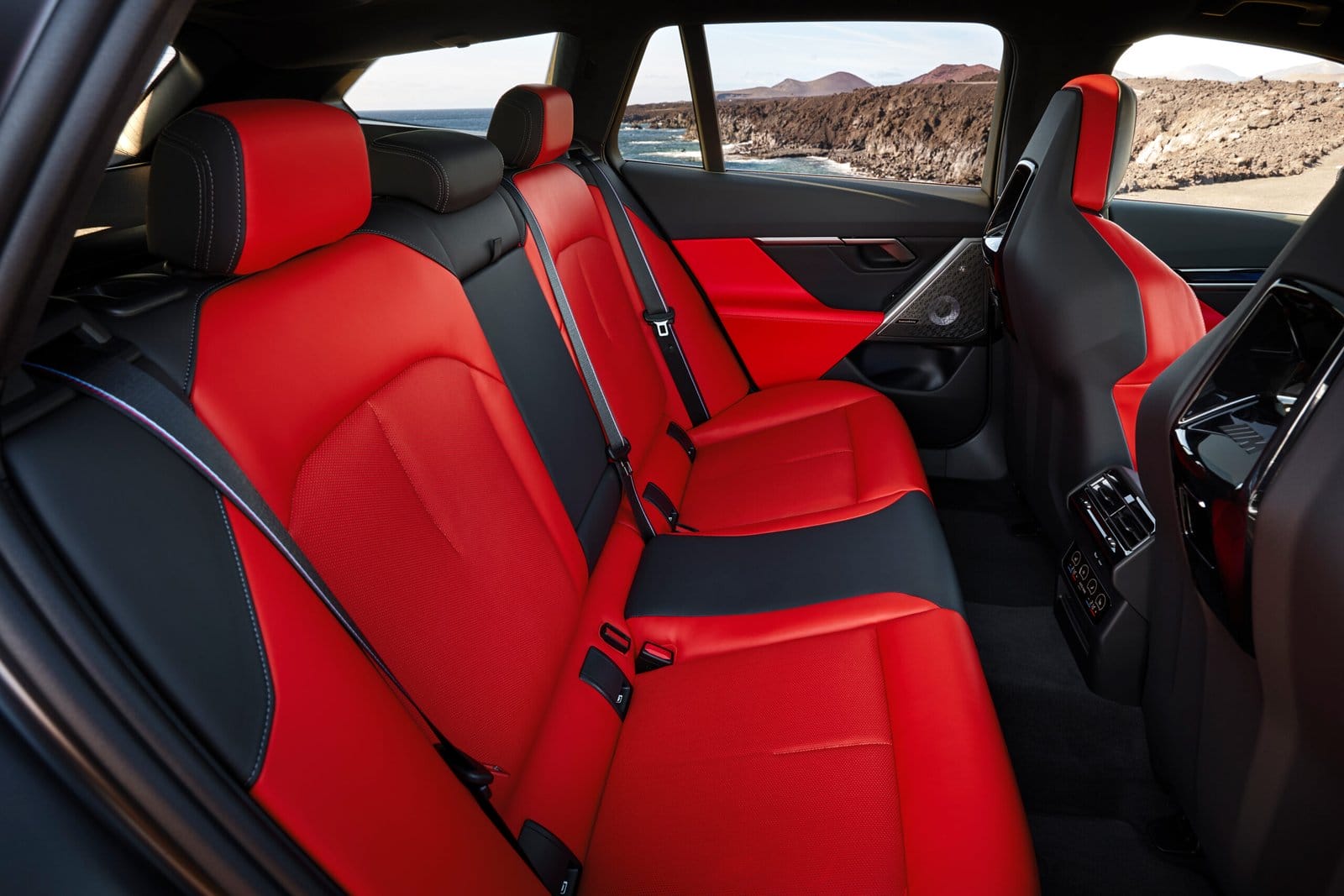 Rear passenger seats of BMW M5 Touring Plug-in Hybrid in red and black leather with M seatbelts and rear climate controls