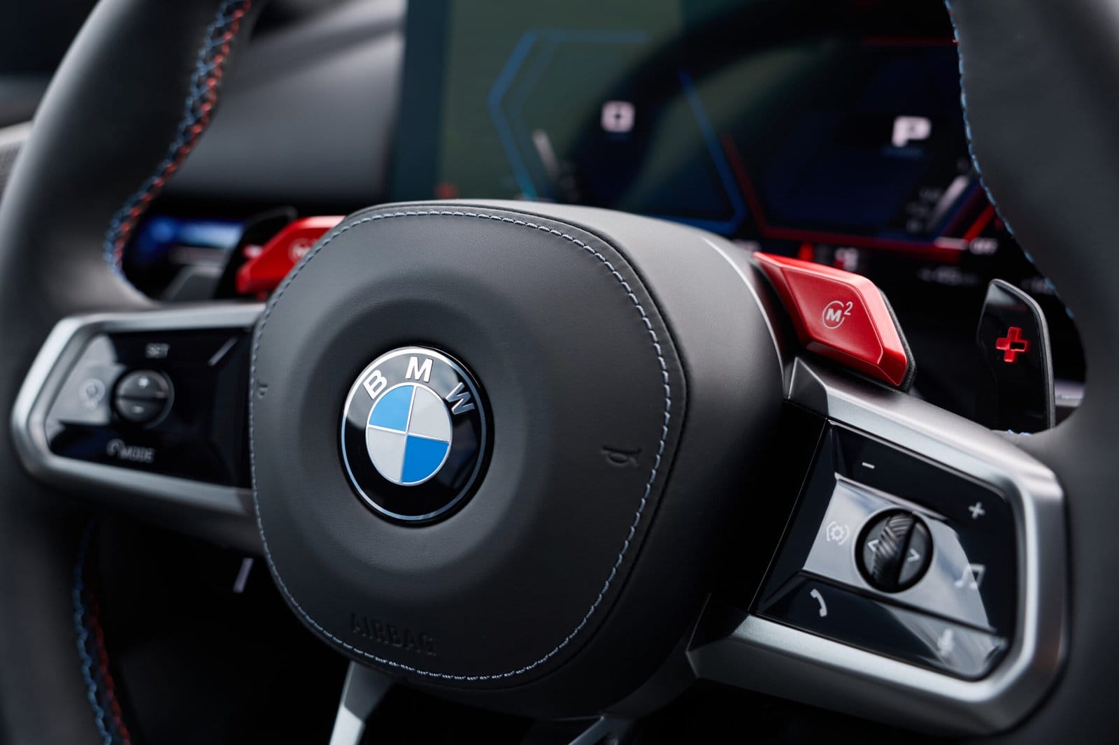 Detailed view of the 2025 BMW M5 Touring Plug-in Hybrid steering wheel with red M buttons