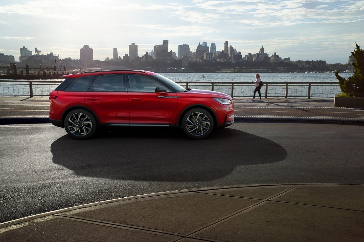Lincoln Corsair Grand Touring electric vehicle parked near a river with an urban skyline in the background