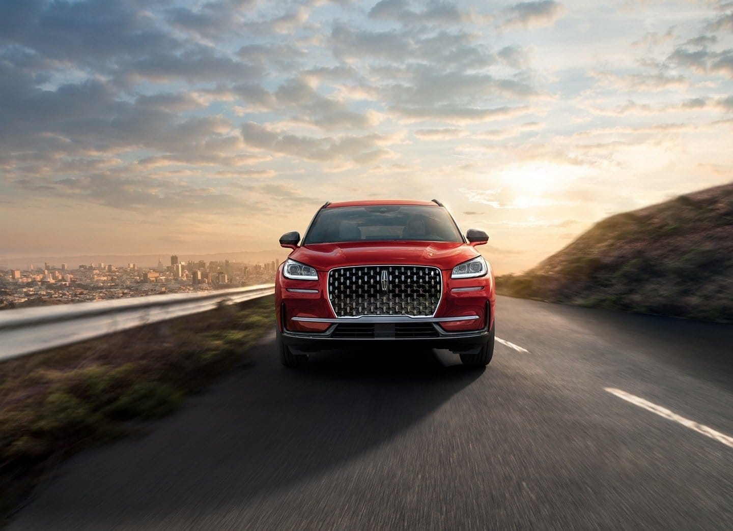 Front view of Lincoln Corsair Grand Touring electric vehicle on a scenic road at sunset