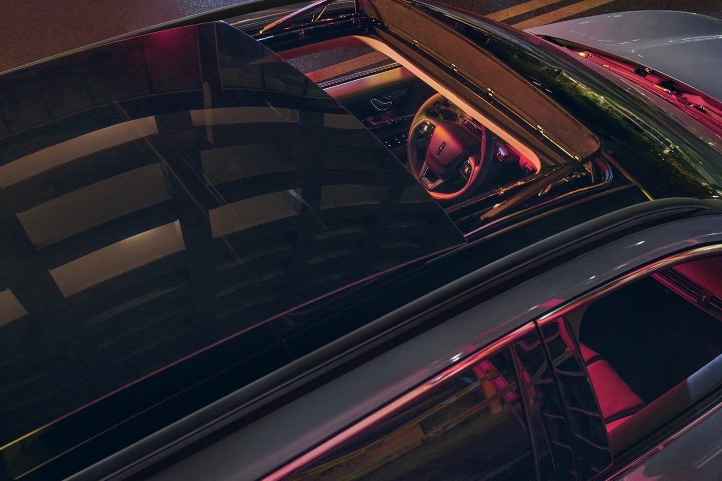 Top view of Lincoln Corsair Grand Touring plug-in hybrid showing illuminated cabin through open sunroof at night