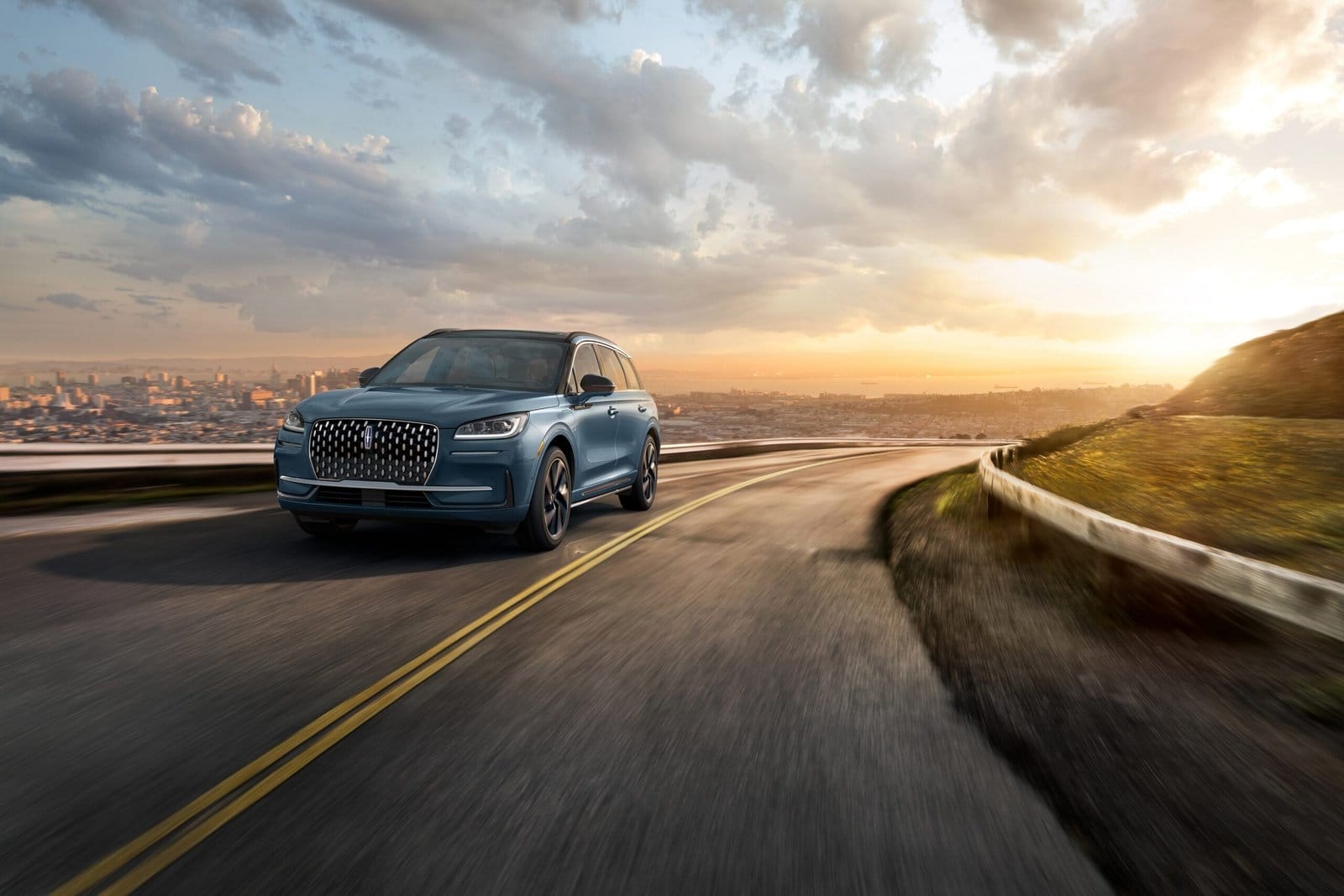 Lincoln Corsair Grand Touring plug-in hybrid driving along a winding road with sunset in the background