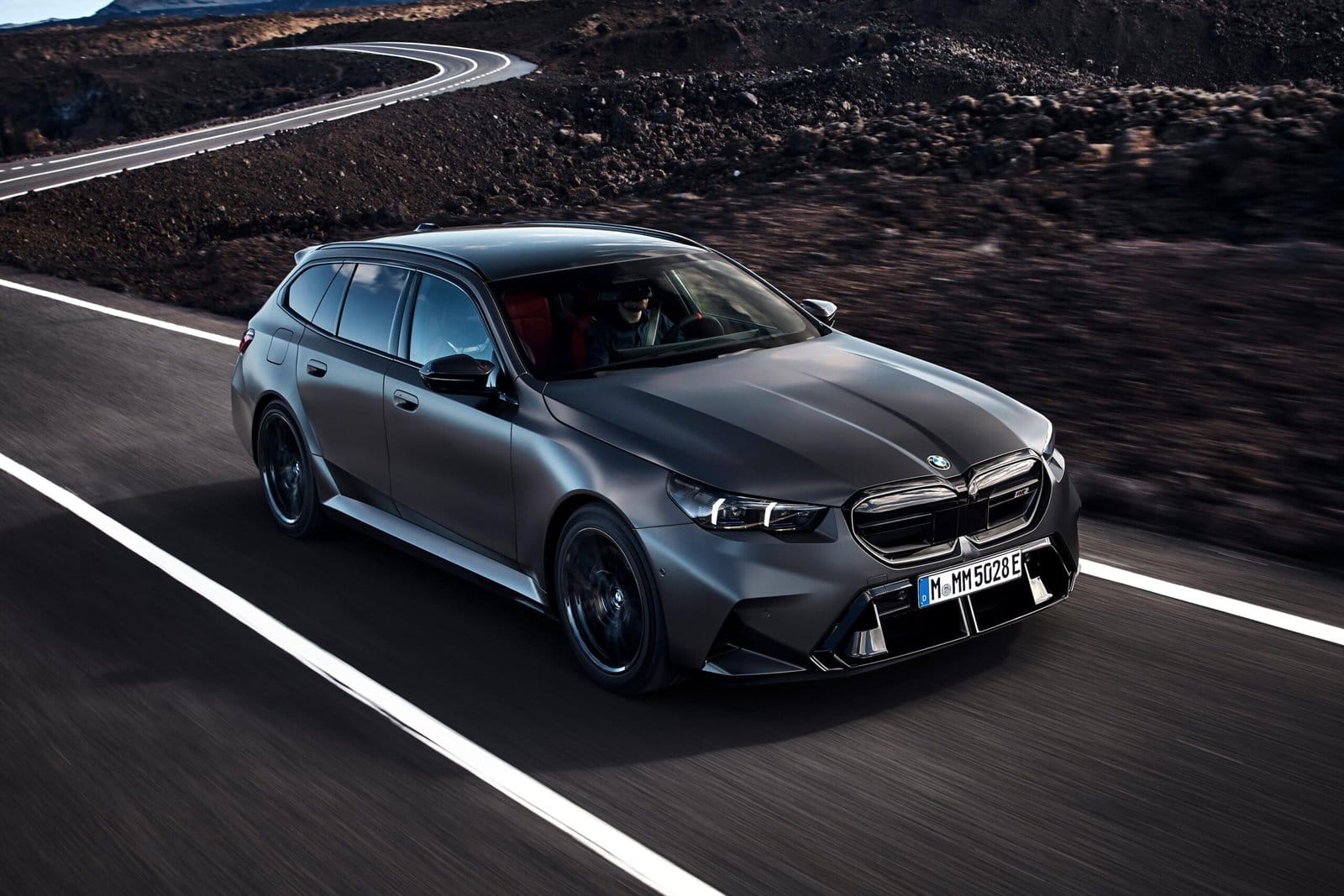 Front-side view of BMW M5 Touring Plug-in Hybrid in motion on a curved mountain road
