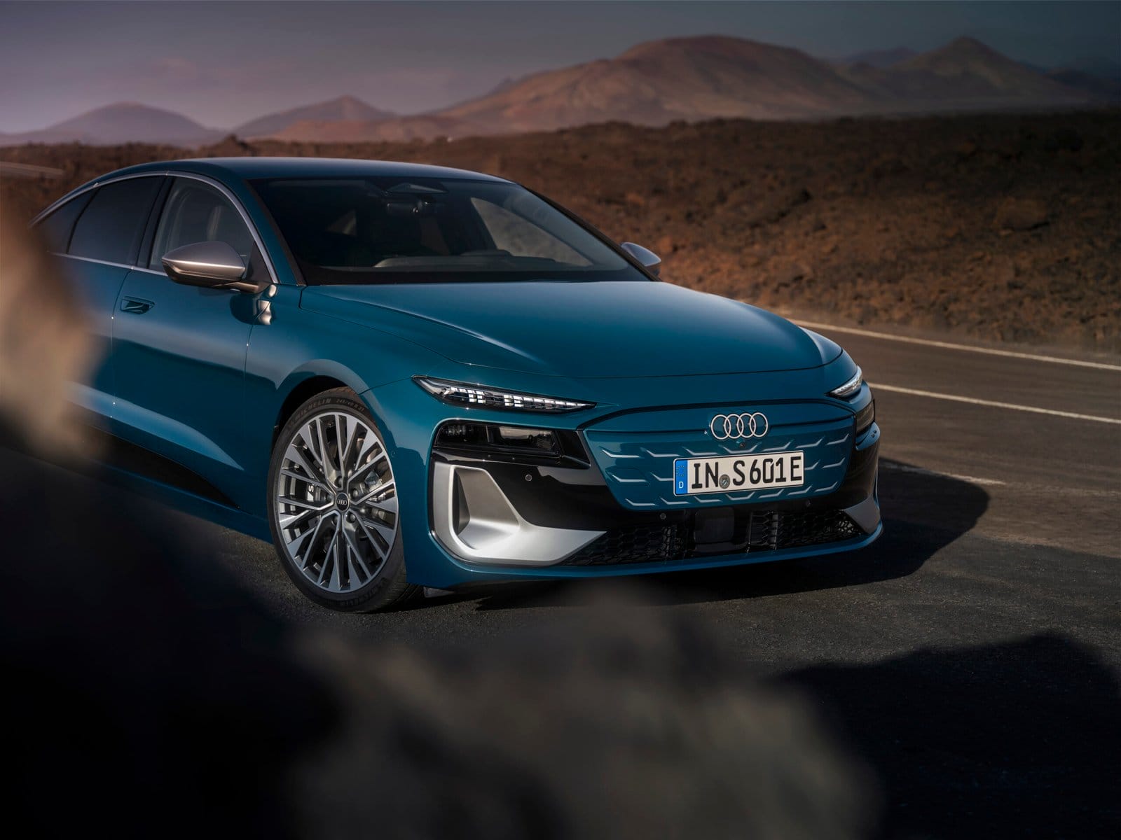 Front side view of Audi S6 e-tron electric vehicle showing headlights, grille, and alloy wheels on a mountain road.