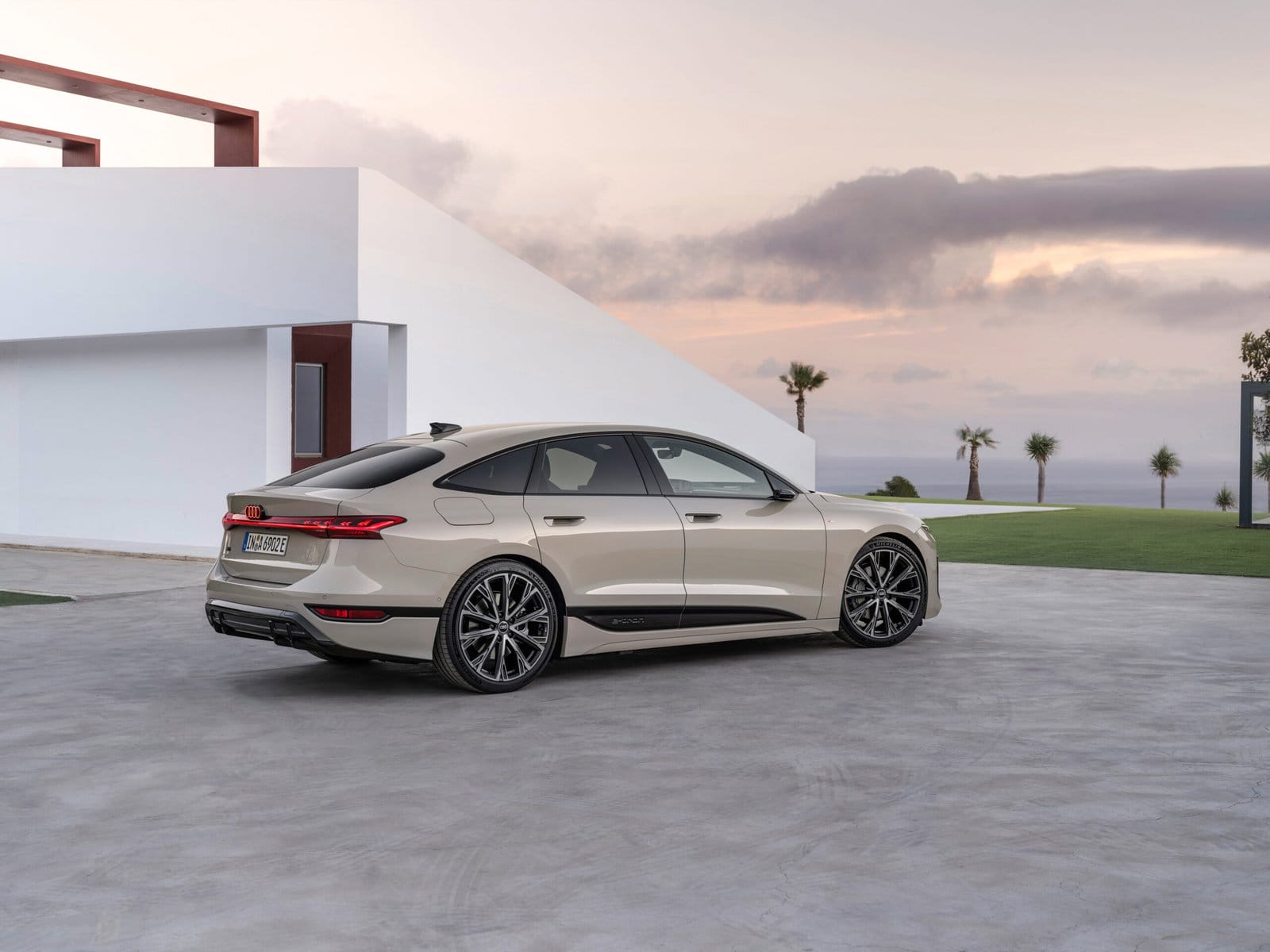 Rear side angle of the 2025 Audi A6 e-tron electric vehicle parked near a modern house