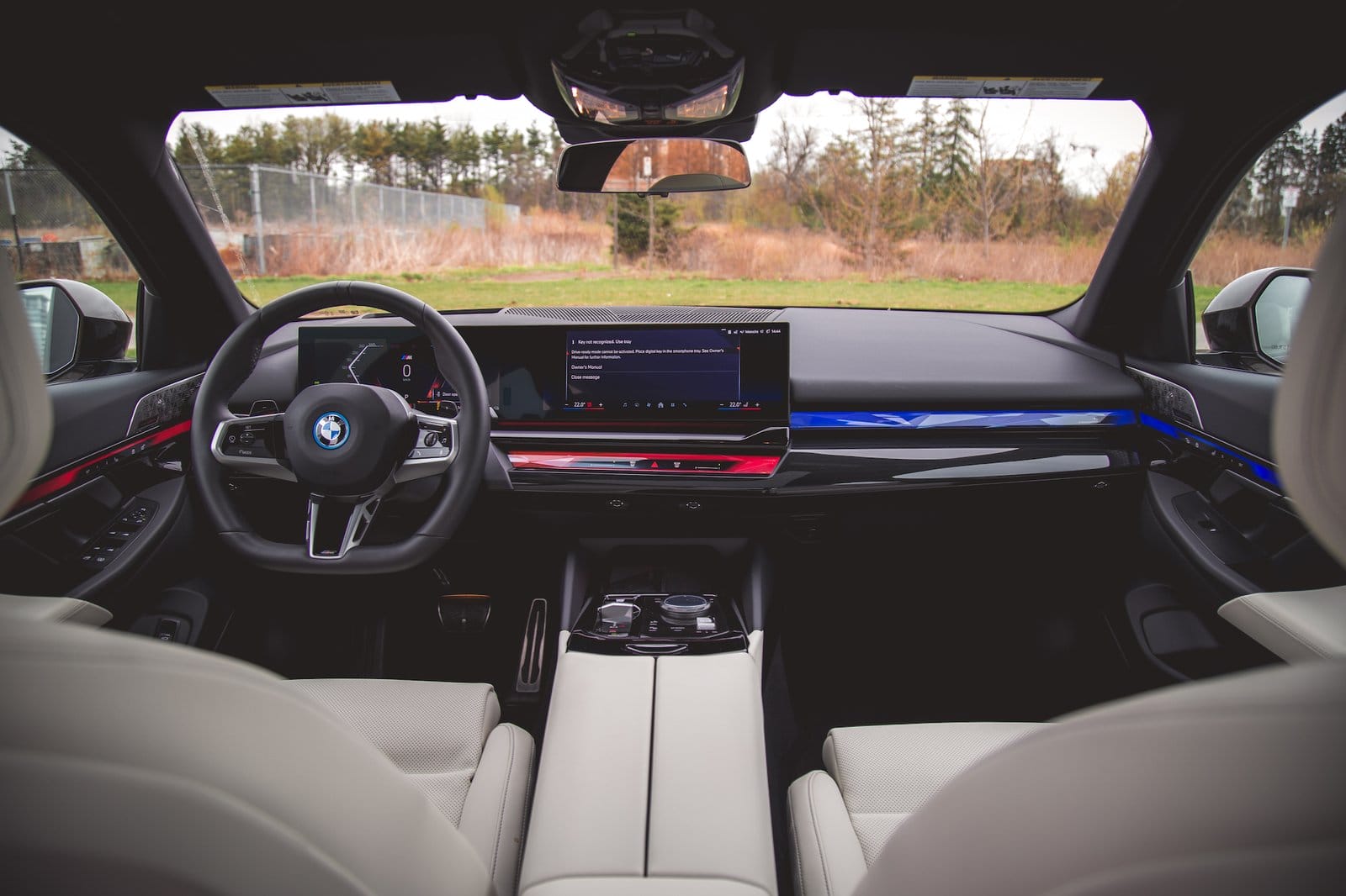 Interior view of BMW 550e xDrive electric vehicle dashboard, steering wheel, and center console from rear seats