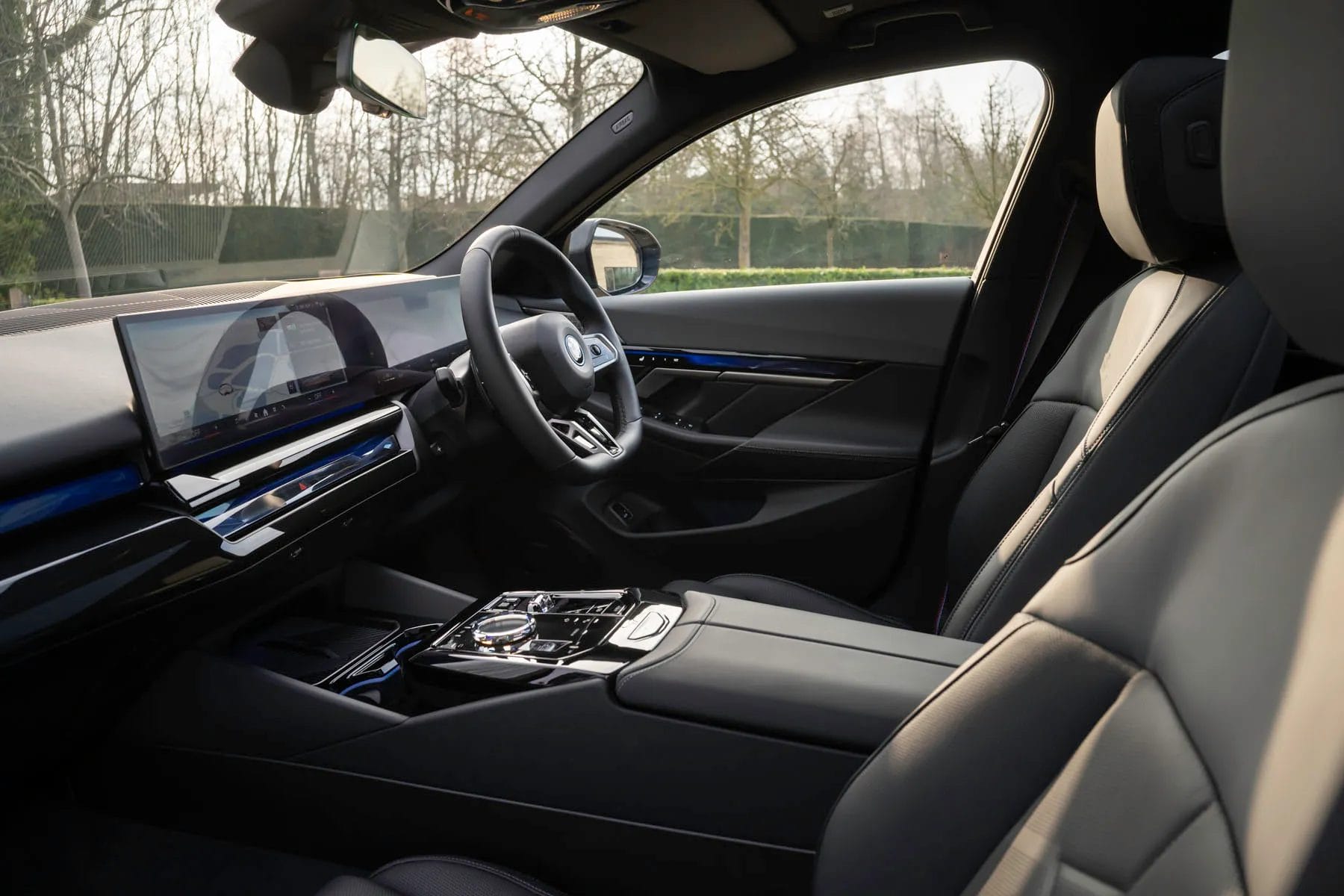 BMW 550e xDrive electric vehicle interior showing steering wheel, digital displays, and premium seats