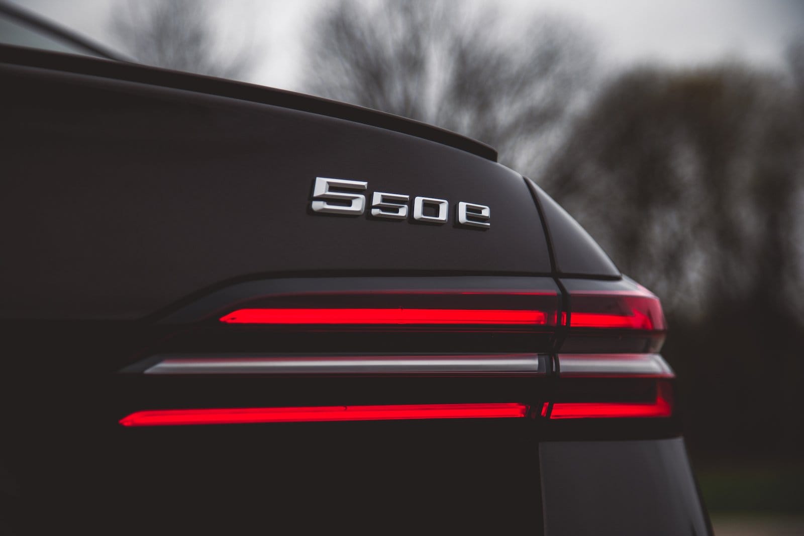 Close-up of BMW 550e xDrive electric vehicle rear badge with illuminated taillights