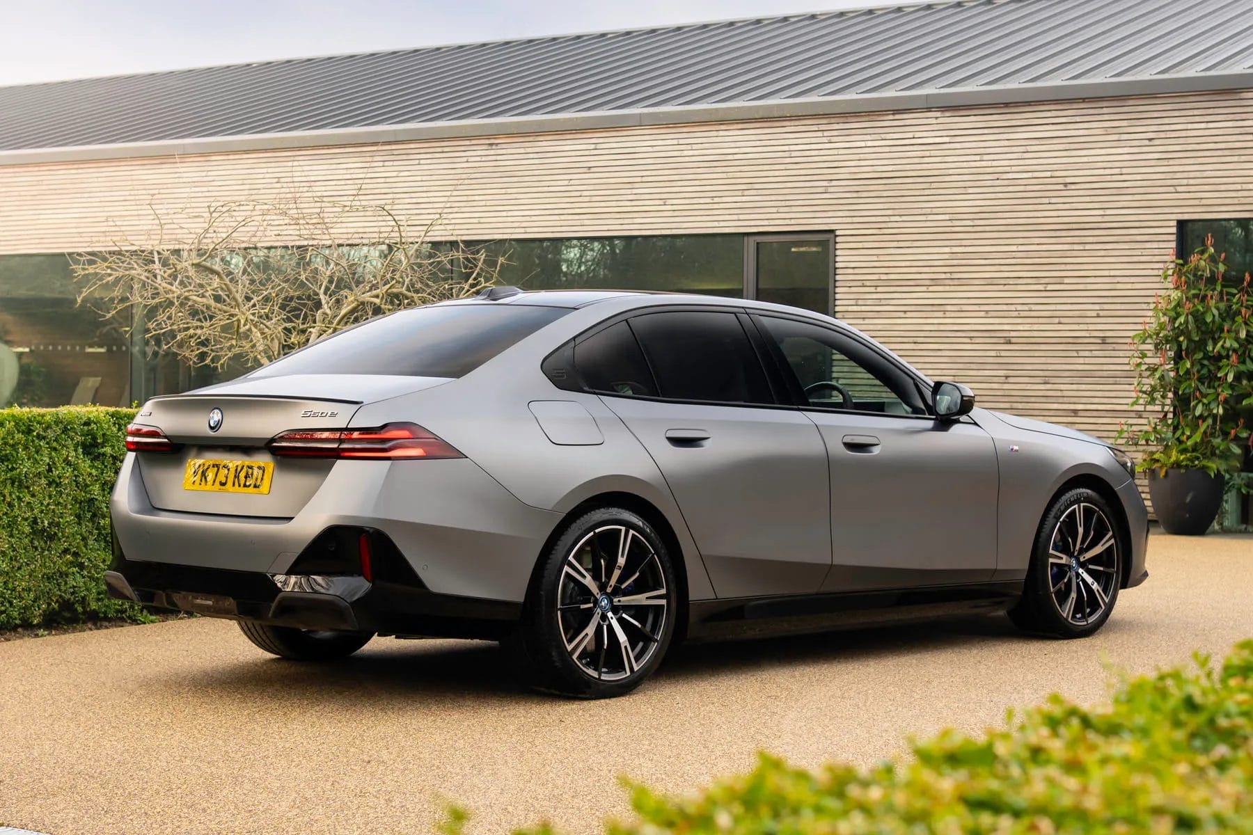 BMW 550e xDrive electric vehicle rear side angle view parked outside a modern building