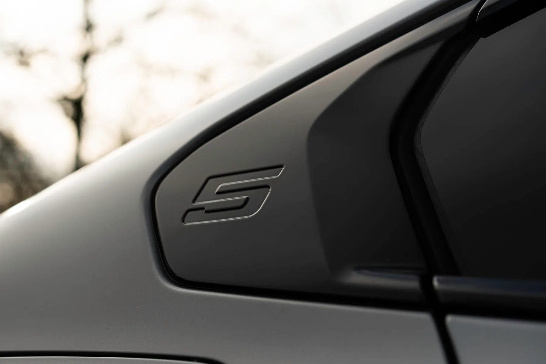 Close-up of the BMW 550e xDrive electric vehicle S badge on the C-pillar